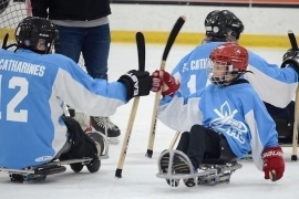 Two people playing sledge hockey