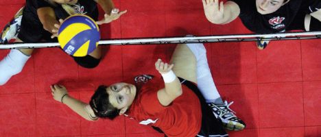 top view of sitting volleyball players lobbing the ball over the net