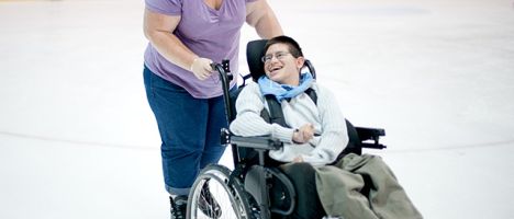 woman pushing a child in a wheelchair in an ice rink